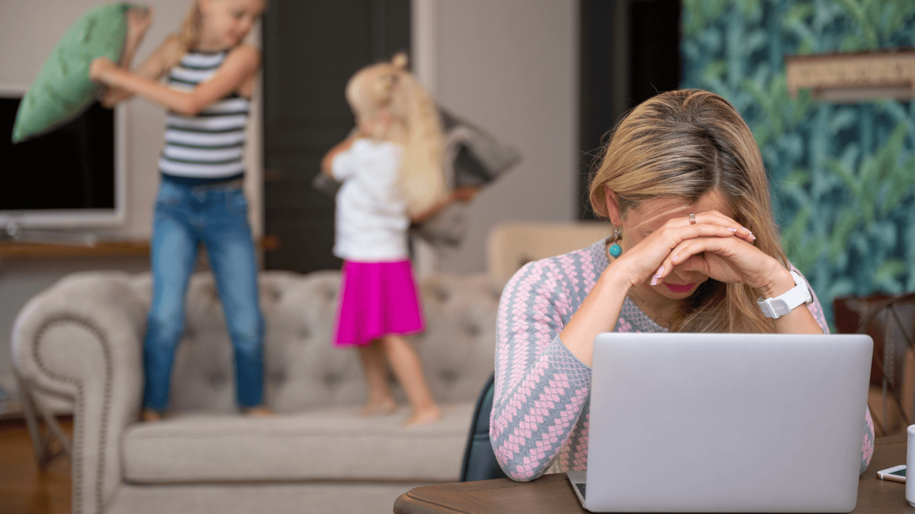 Exhausted mom with children misbehaving and experiencing burnout from working at home.